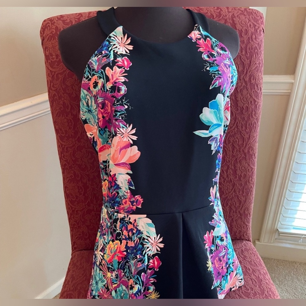 Black and floral print knit top with cross straps
and peplum. Nicole Miller